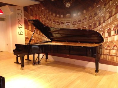 Piano à queue Fazioli noir devant un décor de théâtre